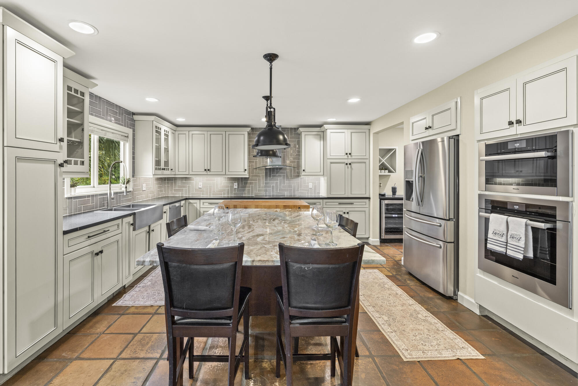 6595 Wood Lake Road Jupiter, FL 33458 - Photo 14 of 54 a kitchen with stainless steel appliances granite countertop a dining table chairs refrigerator and cabinets