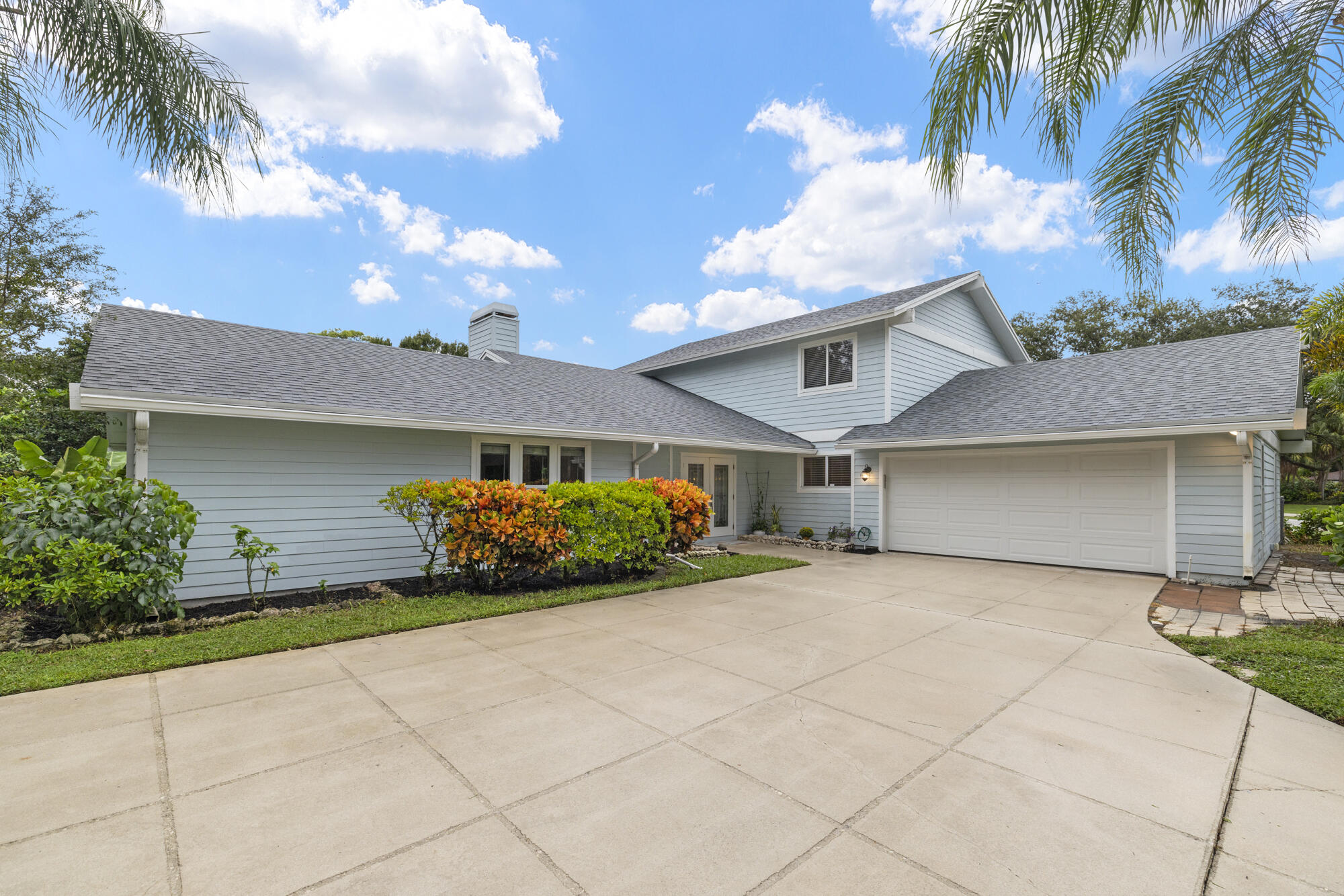 6595 Wood Lake Road Jupiter, FL 33458 - Photo 2 of 54 a front view of a house with a garden and entryway