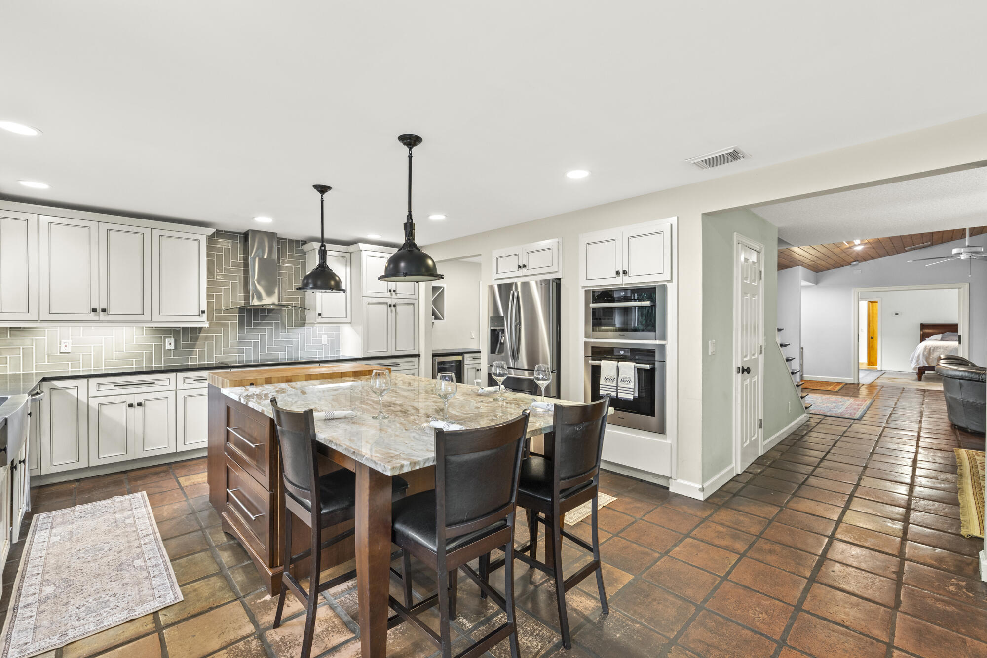 6595 Wood Lake Road Jupiter, FL 33458 - Photo 23 of 54 a kitchen with stainless steel appliances kitchen island granite countertop a table chairs and a refrigerator