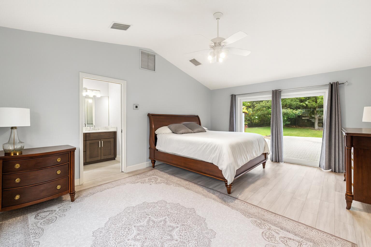 6595 Wood Lake Road Jupiter, FL 33458 - Photo 29 of 54 a bedroom with a large bed and a lamp on dresser