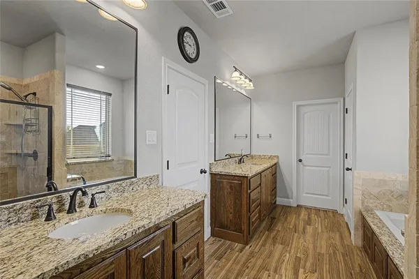 a bathroom with a granite countertop double vanity sink and mirror