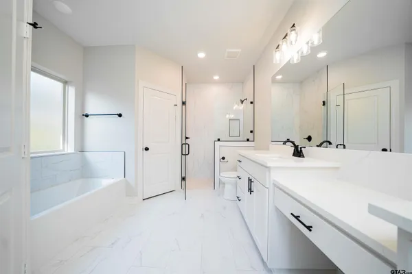 a spacious bathroom with a double vanity sink a mirror and a bathtub