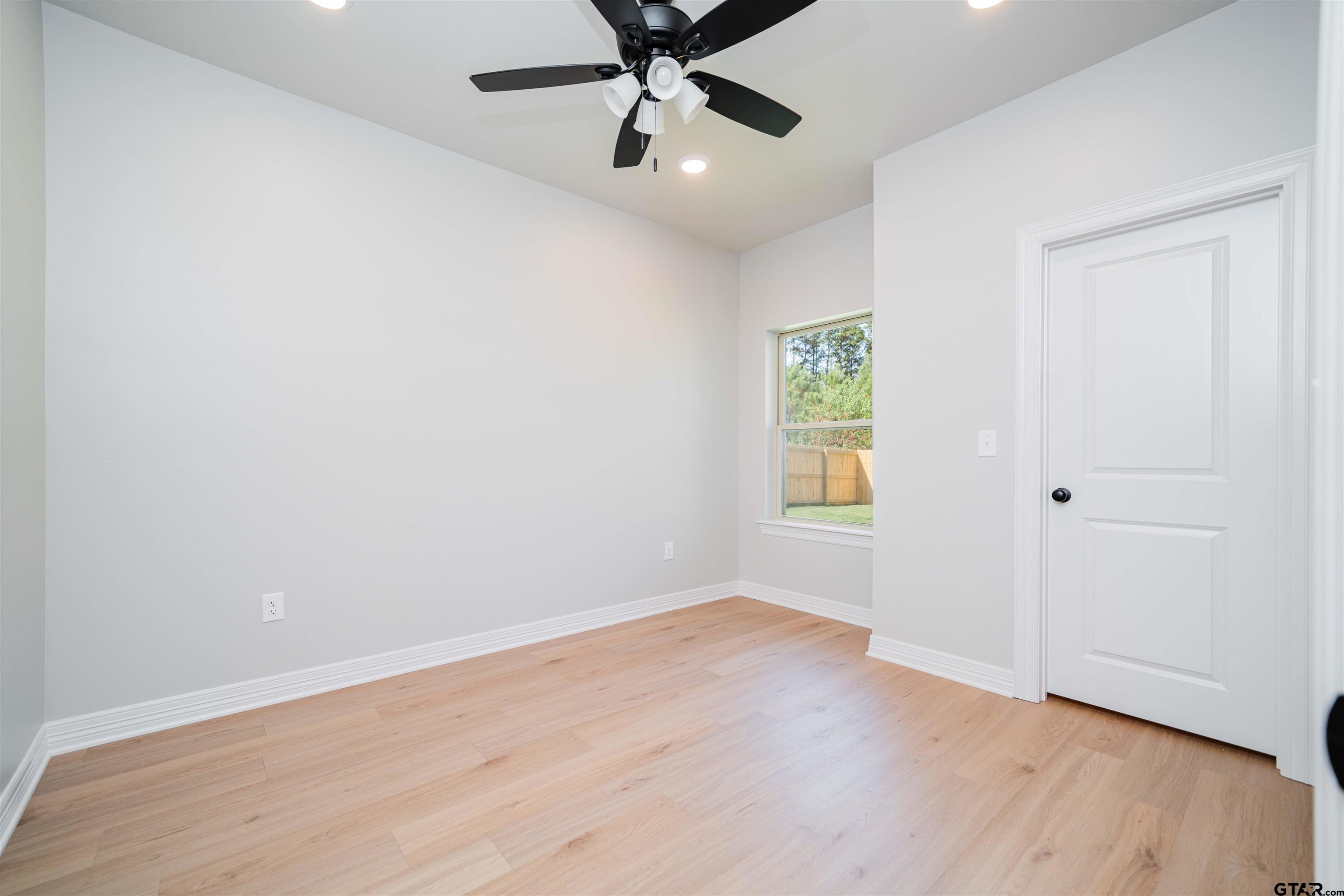 1203 Penny Lane Kilgore, TX 75662 - Photo 16 of 24 an empty room with wooden floor chandelier fan and windows