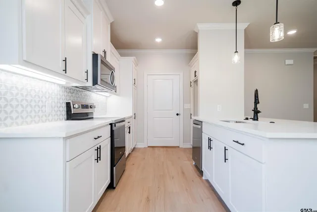 a kitchen with white cabinets appliances and sink