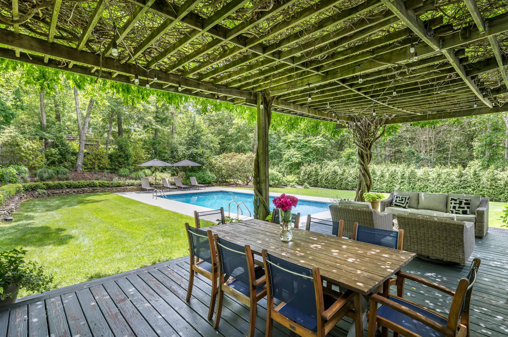 54 Johnson Avenue Southampton, NY 11968 - Photo 4 of 24 a view of a patio with table and chairs under an umbrella with a barbeque grill and couches