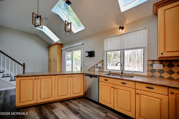 a kitchen with stainless steel appliances granite countertop a sink a stove cabinets and a window