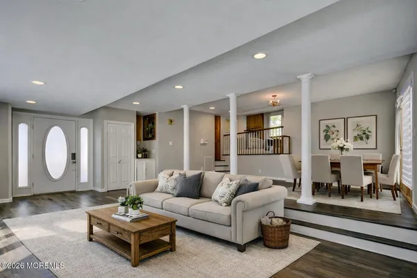 a living room with furniture couches and a dining table with wooden floor