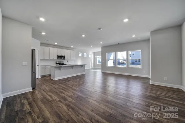a view of an empty room and a kitchen