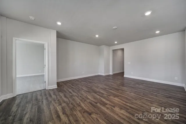 a view of an empty room with wooden floor and closet