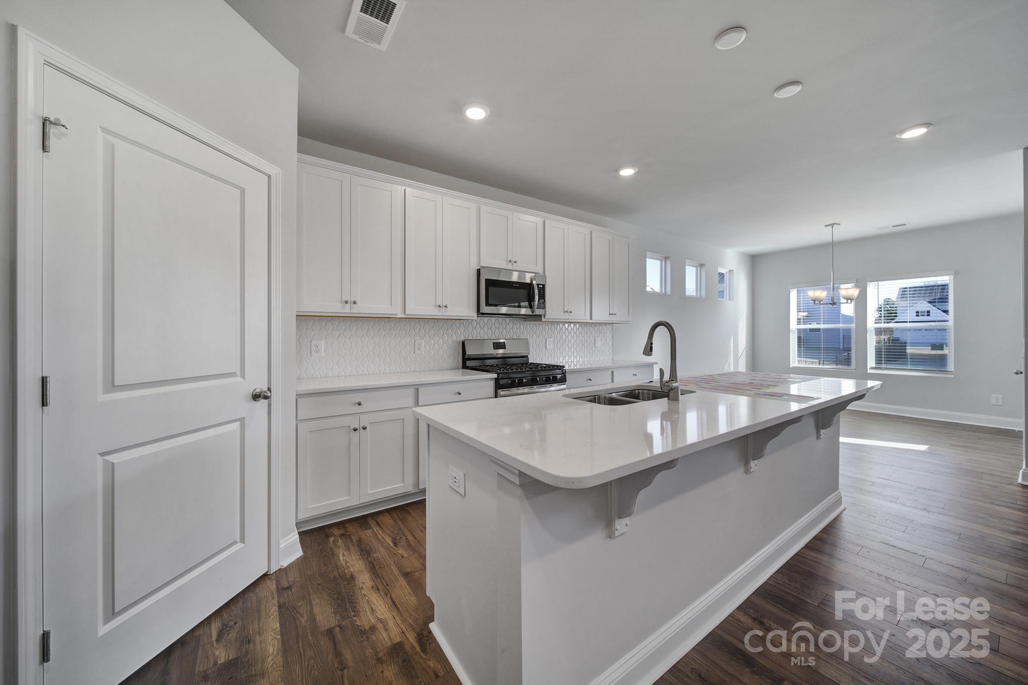 1112 Bradford Pear Road Monroe, NC 28112 - Photo 18 of 33 a large white kitchen with a sink and dishwasher a stove top oven with wooden floor
