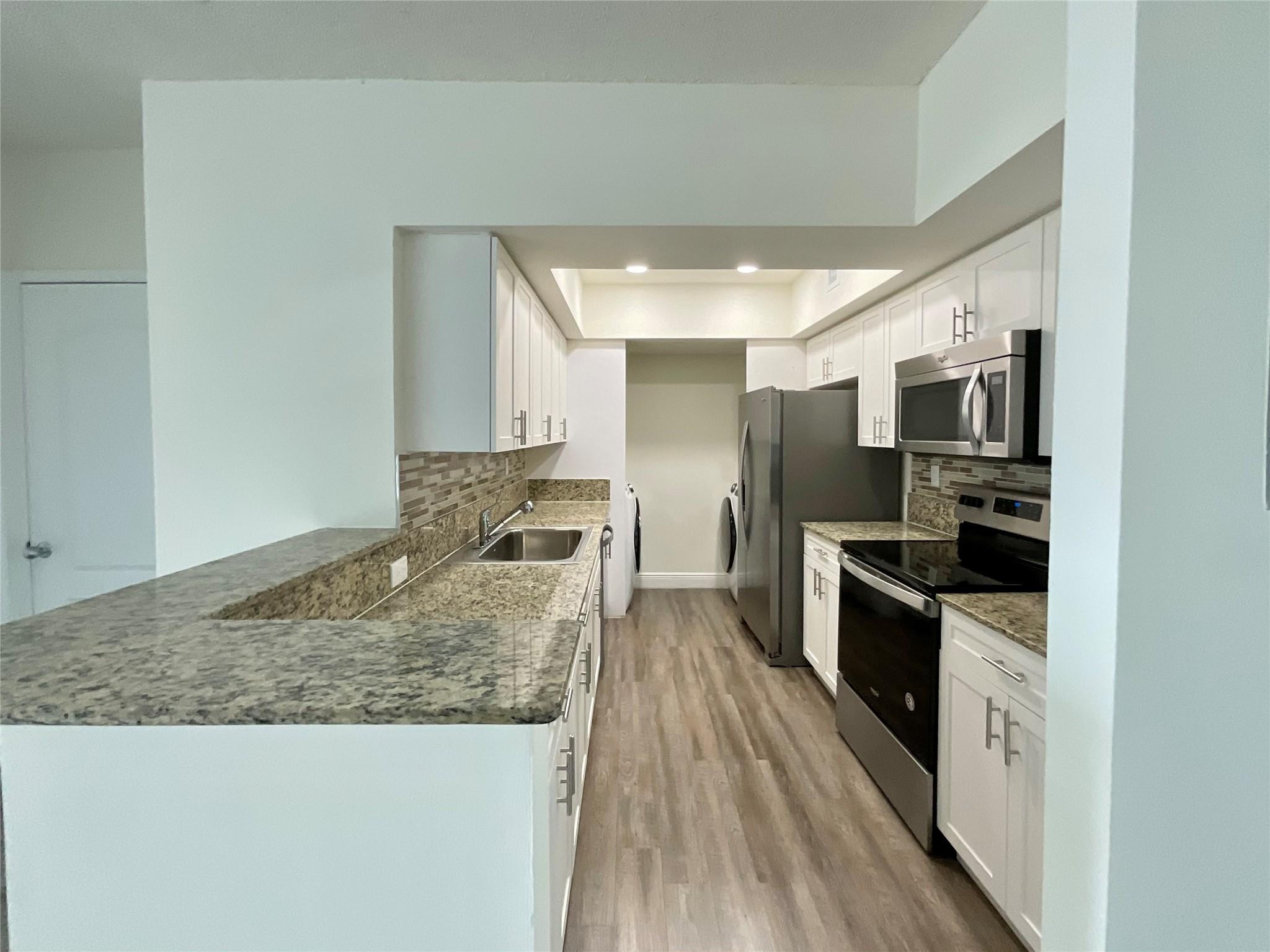 16900 North Bay Road, Unit 21211 Sunny Isles Beach, FL 33160 - Photo 1 of 30 a kitchen with granite countertop a stove top oven and refrigerator