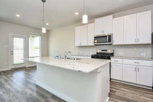 a kitchen with stainless steel appliances granite countertop a sink a stove a microwave a center island and cabinets