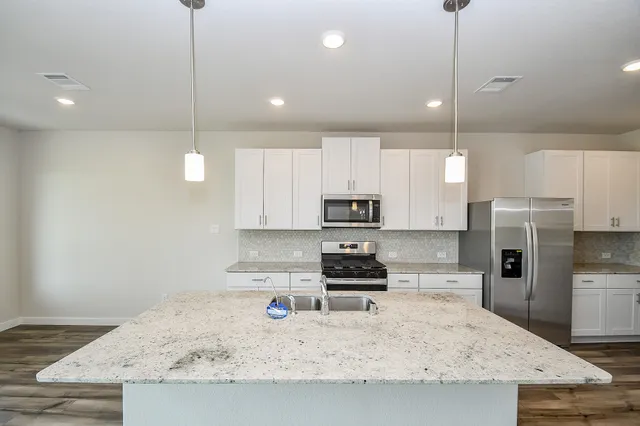 a kitchen with stainless steel appliances granite countertop a sink refrigerator and cabinets