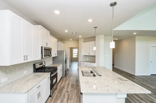 a kitchen with kitchen island granite countertop a sink appliances and cabinets