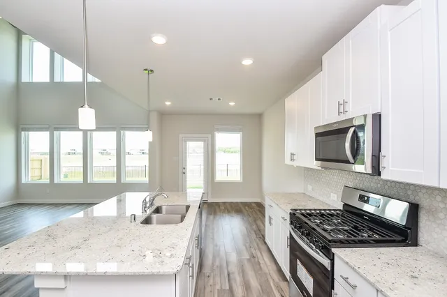 a kitchen with stainless steel appliances granite countertop a stove a sink and a microwave