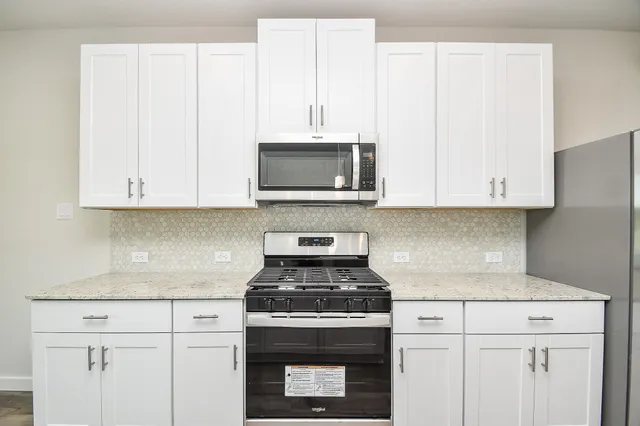 a kitchen with stainless steel appliances granite countertop white cabinets a stove top oven