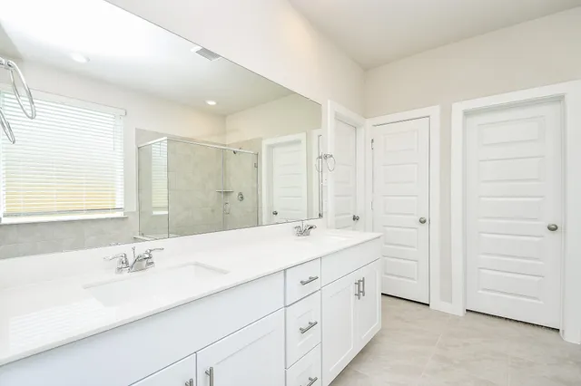 a bathroom with a double vanity sink a large mirror and a bathtub