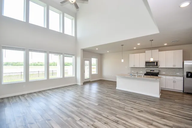 a kitchen with stainless steel appliances granite countertop a stove a sink dishwasher and a oven with white cabinets