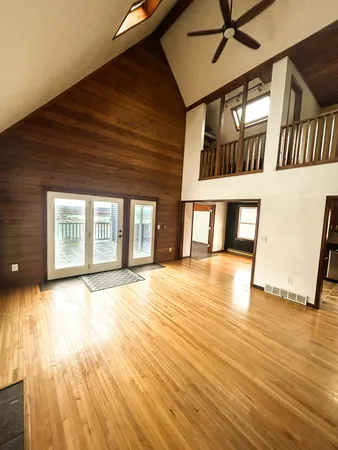 a view of an empty room with wooden floor and a window