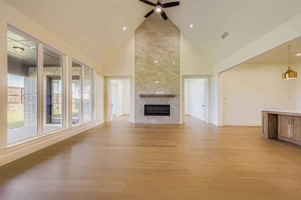 1906 M3 Ranch Road Mansfield, TX 76063 - Photo 6 of 29 Unfurnished living room featuring high vaulted ceiling, light wood-style flooring, a high end fireplace, and a ceiling fan