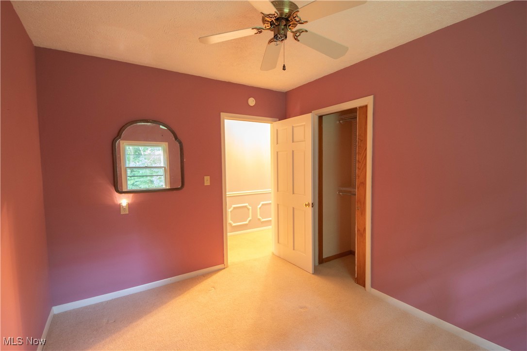 9719 Angling Road Wakeman, OH 44889 - Photo 21 of 39 Unfurnished bedroom featuring light carpet, a closet, ceiling fan, and a textured ceiling