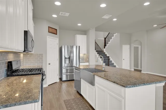 a kitchen with granite countertop a sink a counter and cabinets