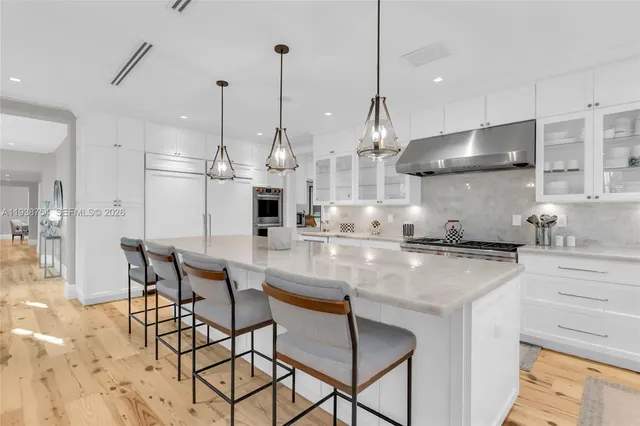 a kitchen with stainless steel appliances granite countertop a stove a sink and a wooden floor