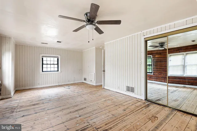 a view of empty room with wooden floor and fan