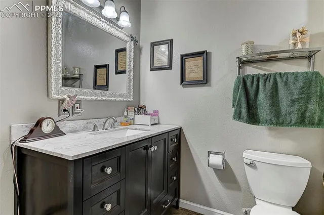 a bathroom with a granite countertop sink and a toilet