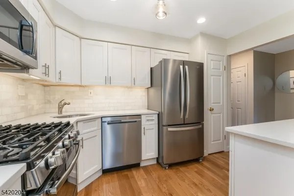 a kitchen with stainless steel appliances a refrigerator a sink and white cabinets