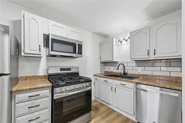 a kitchen with granite countertop white cabinets and stainless steel appliances