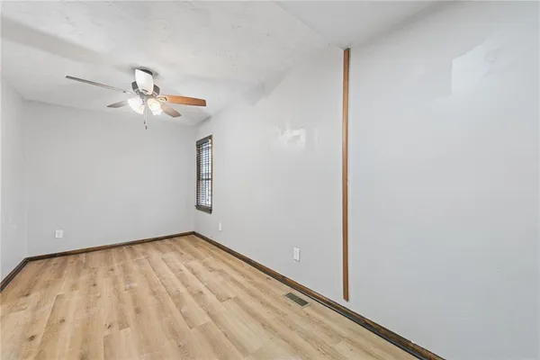 a view of room with a ceiling fan and wooden floor