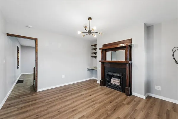 a view of an empty room with wooden floor fireplace and a window