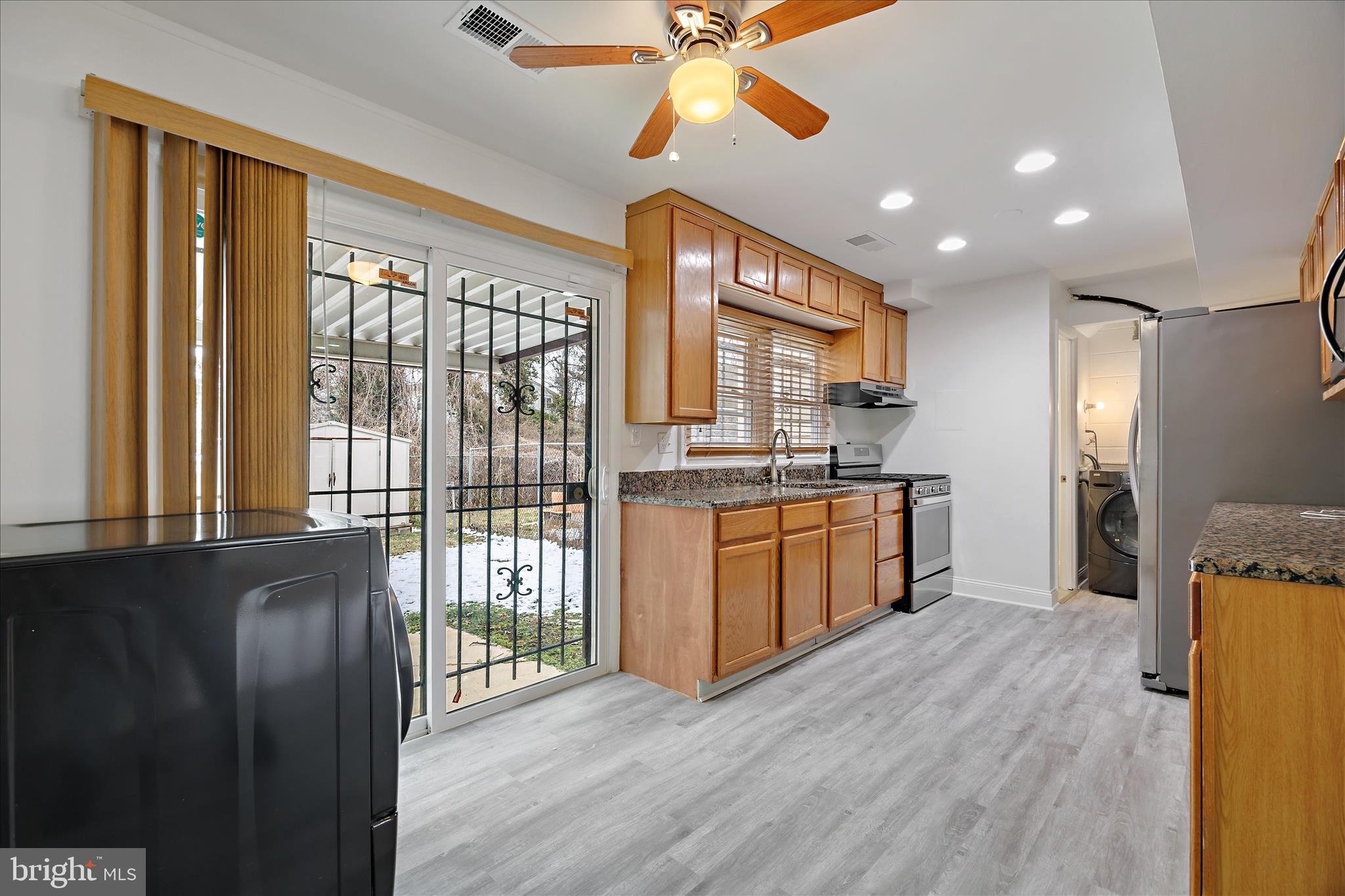 5600 Walker Mill Road Capitol Heights, MD 20743 - Photo 7 of 30 a kitchen with stainless steel appliances granite countertop a refrigerator a sink dishwasher a stove and a dining table with wooden floor