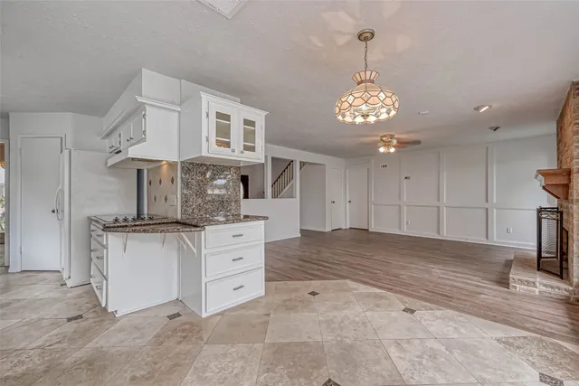 an empty room with wooden floor chandelier fan and windows