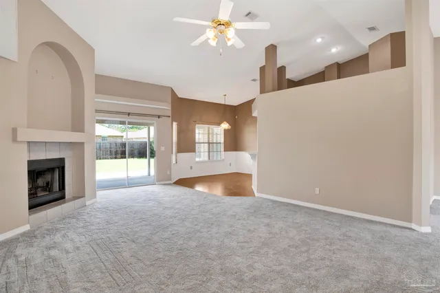 a view of an empty room with kitchen and a window