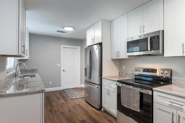 a kitchen with stainless steel appliances granite countertop a refrigerator stove and sink