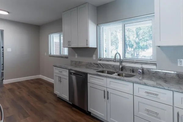 a kitchen with granite countertop white cabinets window and sink
