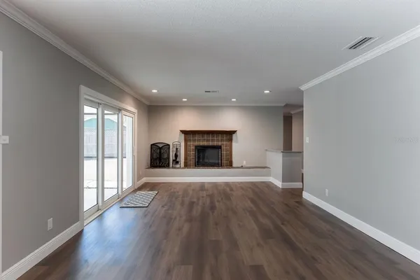 an empty room with wooden floor fireplace and windows