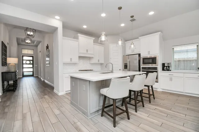 a kitchen with stainless steel appliances a dining table chairs microwave and sink