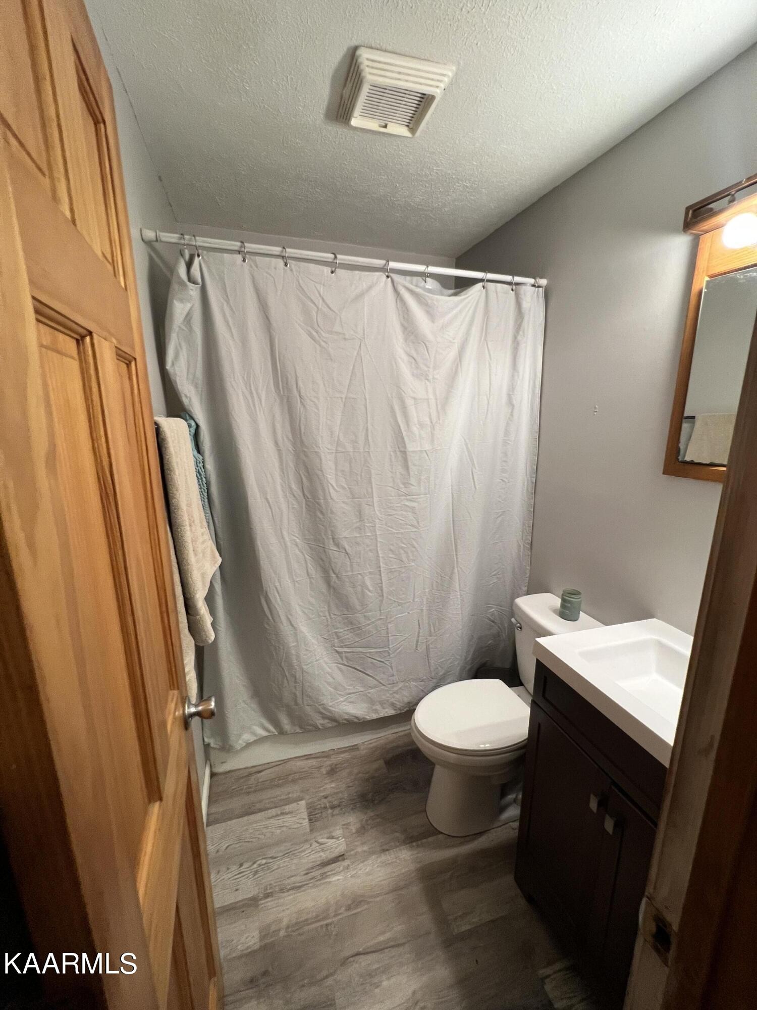 230 Granite Road Clinton, TN 37716 - Photo 12 of 15 a bathroom with a sink a toilet a mirror and shower curtain