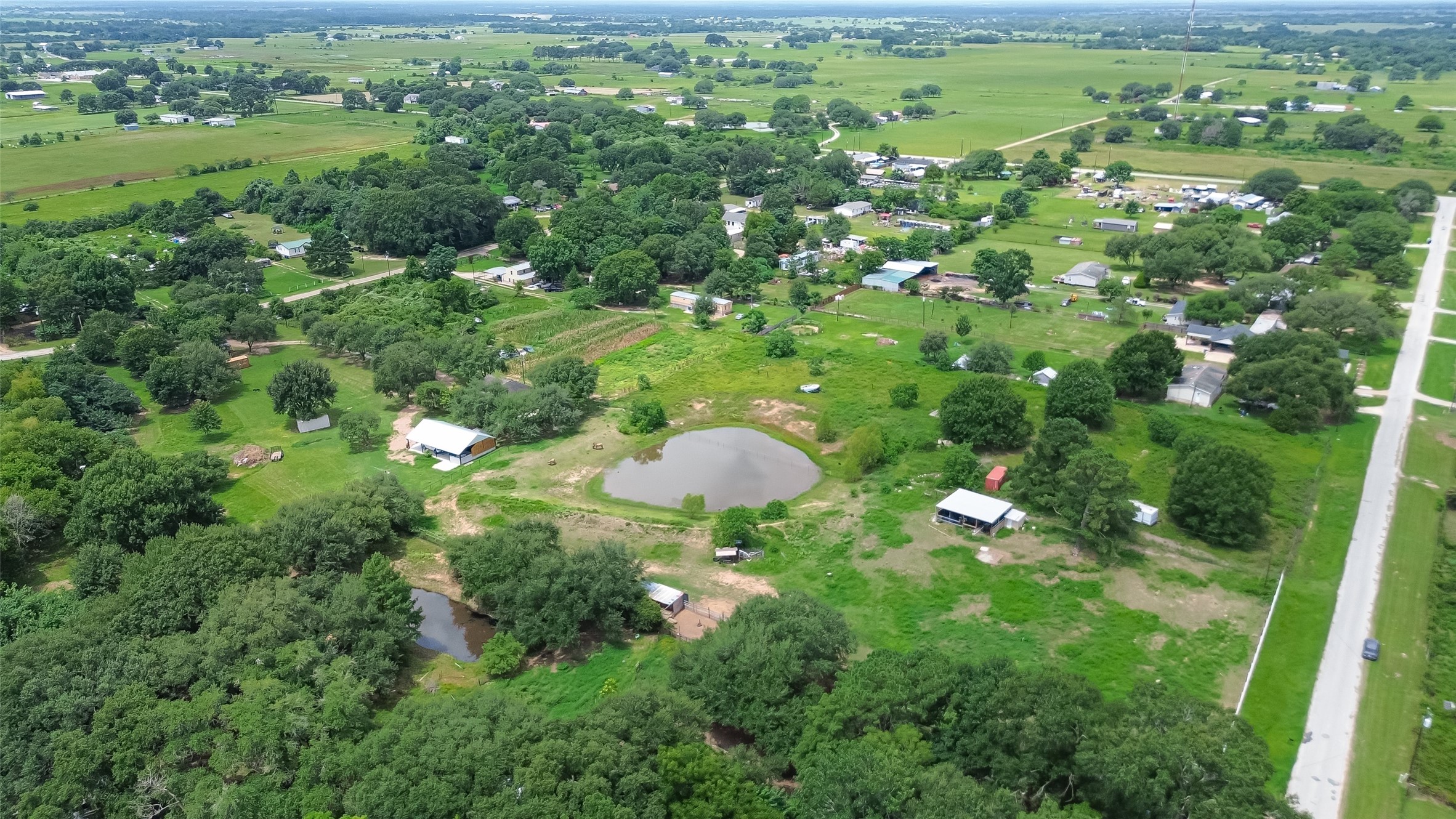 35535 Windmill Road Hempstead, TX 77445 - Photo 27 of 41 This aerial photo showcases a rural community with spacious greenery, scattered homes, and small ponds. The area is lush with trees and open fields, offering a serene countryside setting. Ideal for those seeking tranquility and space.