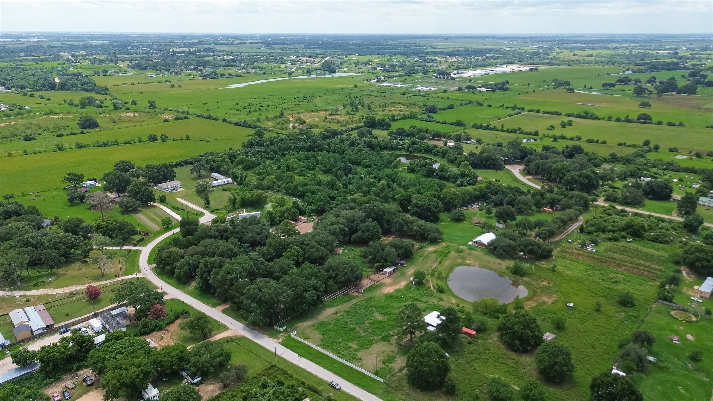 35535 Windmill Road Hempstead, TX 77445 - Photo 35 of 41 This aerial photo showcases a peaceful rural landscape with lush greenery, scattered homes, and a small pond. The expansive open fields and tree-lined roads offer a serene, spacious environment ideal for a countryside lifestyle.