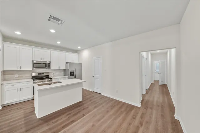 a kitchen with stainless steel appliances a stove top oven a sink and a refrigerator