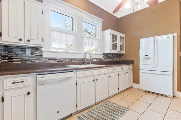 a kitchen with granite countertop white cabinets and refrigerator