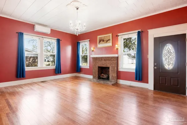 a view of an empty room with window and wooden floor