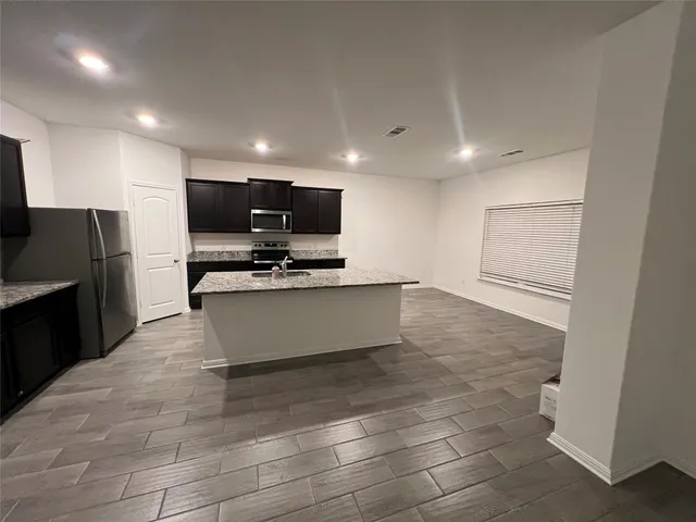 a large kitchen with stainless steel appliances a large counter top and a stove