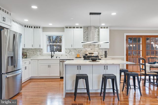 a kitchen with stainless steel appliances granite countertop a dining table chairs refrigerator sink and cabinets