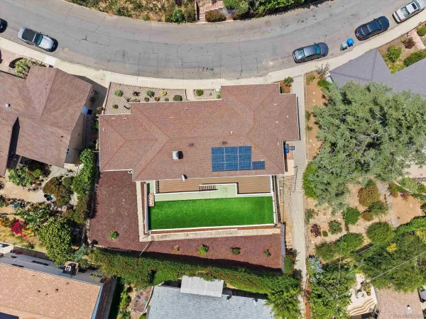 an aerial view of a house with a yard and a large tree
