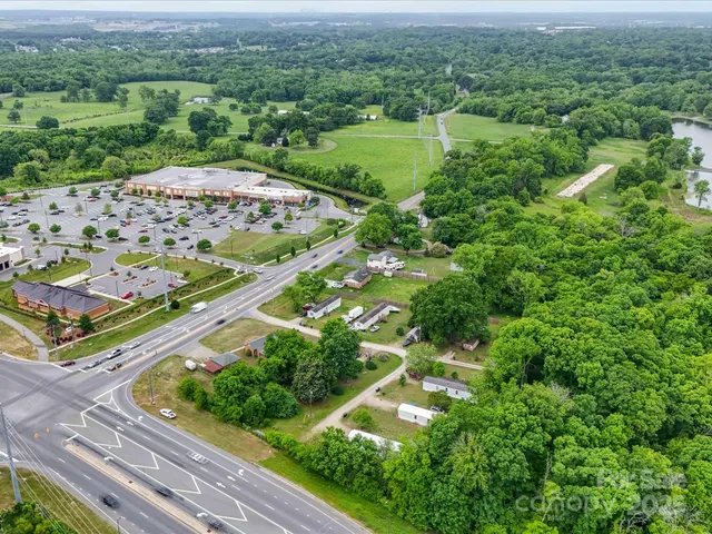 an aerial view of green landscape with trees houses and wooden fence